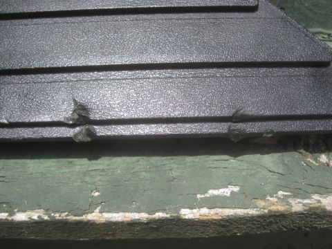 1993 Ford Bronco - Damaged black plastic trim piece with horizontal ridges. Green painted wood is visible below.