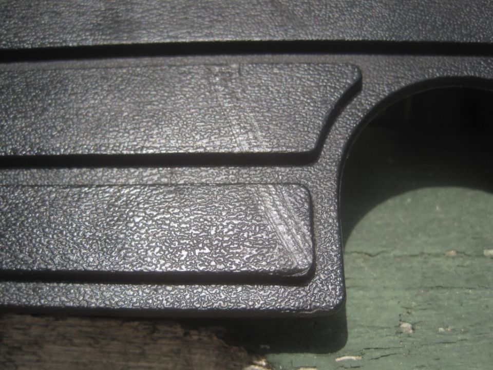 Close-up of a black textured plastic trim piece with some scratches