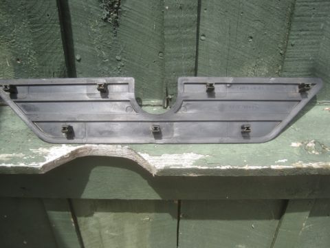 1993 Ford Bronco - A black plastic trim piece with mounting clips is shown against a green wooden background.