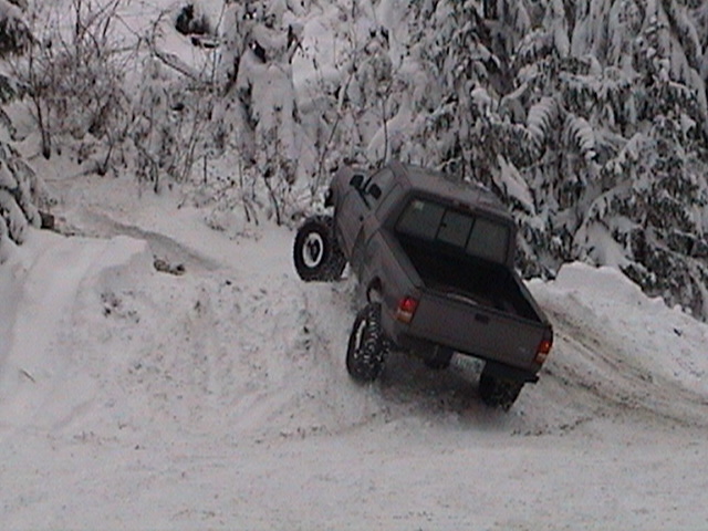 Lifted gray Ranger pickup climbing a snowbank with front wheel lifted off the ground