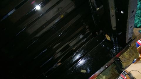 1983 Ford Bronco - Undercarriage of a vehicle, showing ribbed metal panels coated in black paint.
