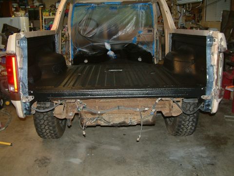 1983 Ford Bronco - The rear of a Ford Bronco shows a newly painted bed and exposed undercarriage, indicating ongoing work.