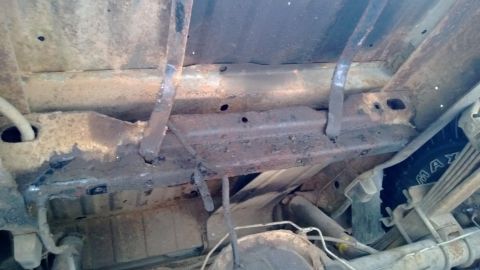 1983 Ford Bronco - Undercarriage view showing frame, suspension, and tire of an older vehicle.