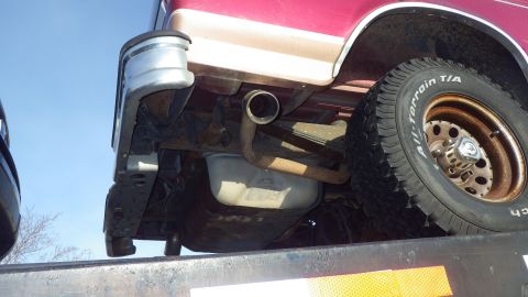 1995 Ford Bronco - Undercarriage view shows the exhaust system, fuel tank, and rear tire of a truck.