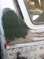 1996 Ford Bronco - Body filler being applied to a car door during repair work.