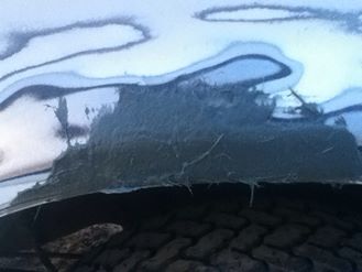 1996 Ford Bronco - Body filler is applied to repair damage on the vehicle's fender well.
