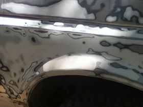 1996 Ford Bronco - Body panel of a vehicle undergoing repair, covered in body filler and primer.