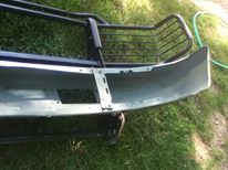 1996 Ford Bronco - A detached front bumper and brush guard assembly rests on grass.