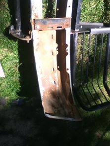 1996 Ford Bronco - Close-up of a heavily rusted bumper section with visible mounting hardware and a portion of a black grille.