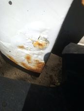 1996 Ford Bronco - A close-up of a rusty vehicle fender shows damage and a website logo.