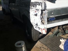1996 Ford Bronco - Rear view of a damaged white vehicle, showing a missing taillight and dented quarter panel.