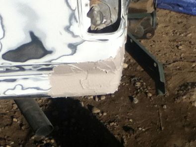 1996 Ford Bronco - The rear quarter panel of a 1996 Ford Bronco is undergoing bodywork, with visible primer and filler.