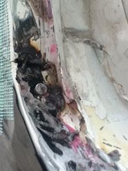 1996 Ford Bronco - This photo shows a close-up of a damaged vehicle panel, revealing rust and debris.