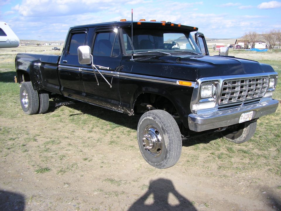Black 1970s Ford crew cab dually pickup on grass with chrome grille and mirrors