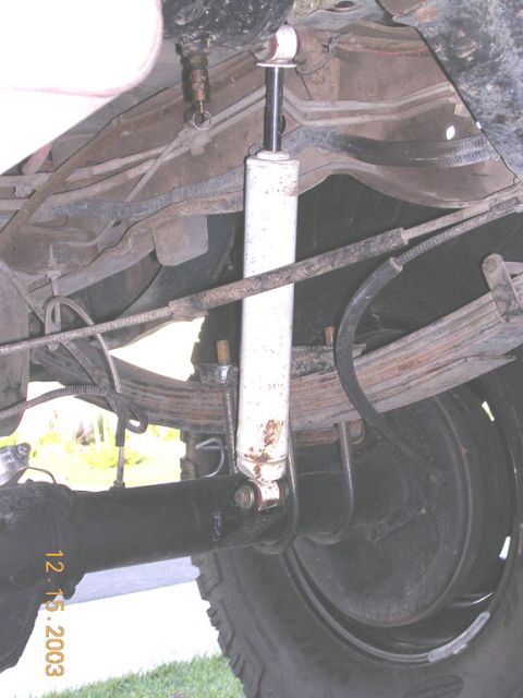 1994 Ford Bronco - Close-up view of a vehicle's rear suspension system, showing leaf springs and a shock absorber.