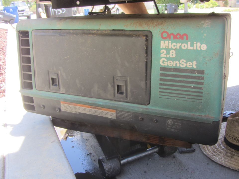 Green Onan generator unit with "MicroLite 2.8 GenSet" label. Unit is mounted on a support structure with some liquid underneath