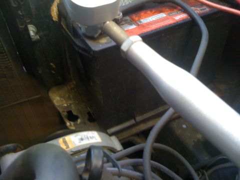 1964 Ford Ranchero - Close-up view of a car battery and some engine parts under the hood.