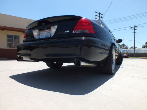 2003 Ford Crown Victoria - low-angle rear shot of a black Ford sedan highlights its SVT badge, dual exhaust, and 'EVIL VTC' license plate.