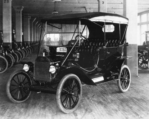1909 Ford Model T - A black 1909 Ford Model T touring car is parked indoors, with a line of similar vehicles in the background.