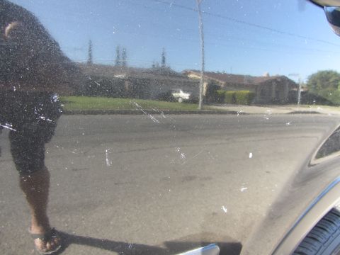 2003 Honda CR-V - Scratched black car door showing reflection of houses and a person's legs.