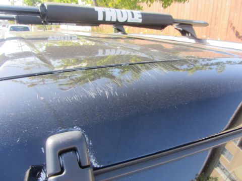 2003 Honda CR-V - The roof of a black SUV shows significant scratching, with a Thule roof rack installed.