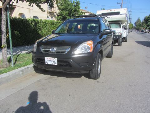2003 Honda CR-V - A dark-colored Honda CR-V is parked on the street, hitched to a large white camper.