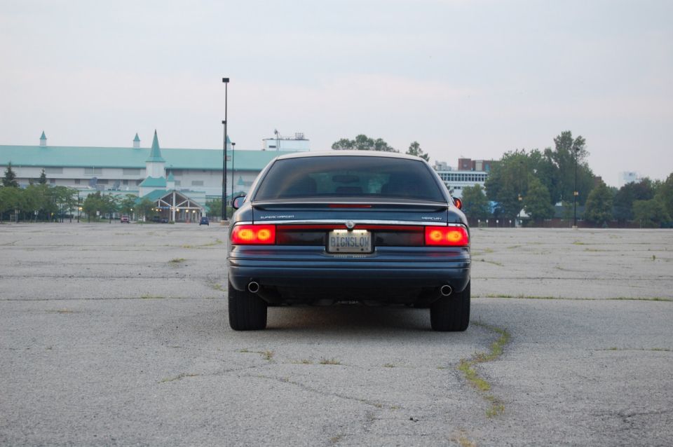 Rear view of dark sedan with brake lights on in an empty parking lot at dusk