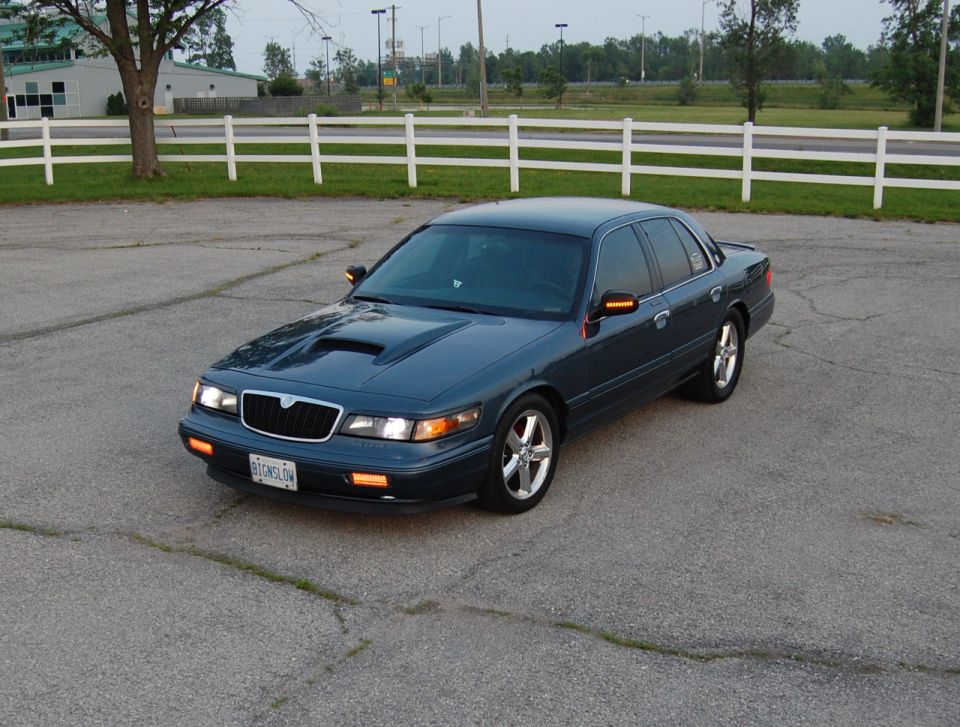 Dark blue sedan with a hood scoop and aftermarket wheels parked on asphalt