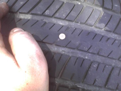 2003 Ford Crown Victoria - A nail is lodged in the tire tread, indicating a puncture.