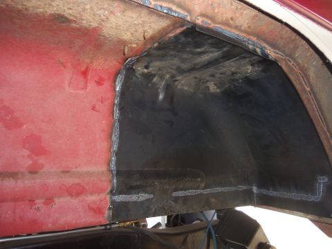 1968 Ford Bronco - Close-up view of a modified rear wheel well on a red vehicle, showing recent welding work.