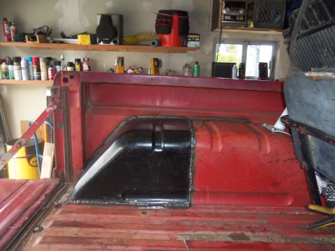 1968 Ford Bronco - Modified rear wheel well in a red pickup truck bed, likely for custom tire clearance.