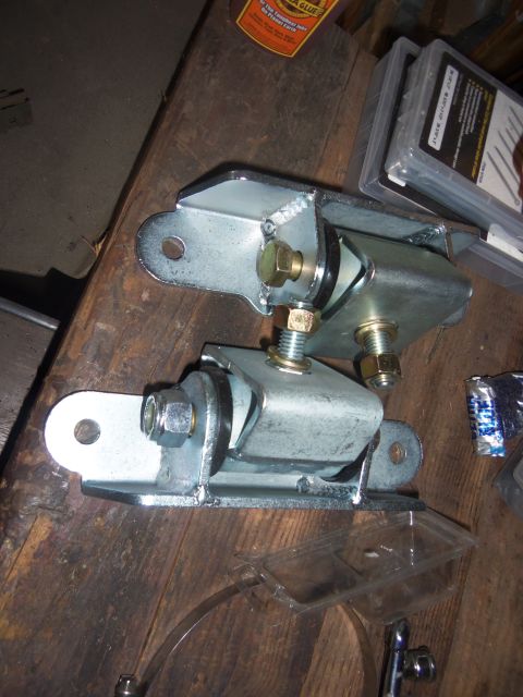 1968 Ford Bronco - Two engine mounts are shown, likely for a vehicle restoration project, with a bottle of glue and a box of fasteners in the background.