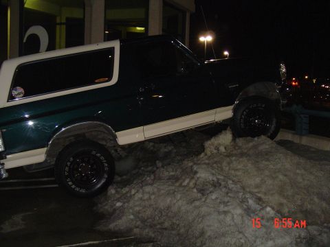 1993 Ford Bronco - A Ford Bronco is parked on a snow pile at night, with streetlights in the background.