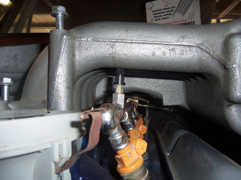 Engine intake manifold with orange fuel injectors and metal fuel lines