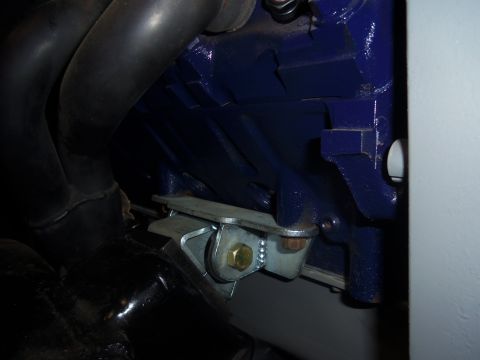 1968 Ford Bronco - Close-up view of an engine block with exhaust pipes and a metal mounting bracket attached.