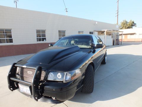 2003 Ford Crown Victoria - Front view of a black Ford Crown Victoria with halo projector headlights, billet grille, and a steel push bar.