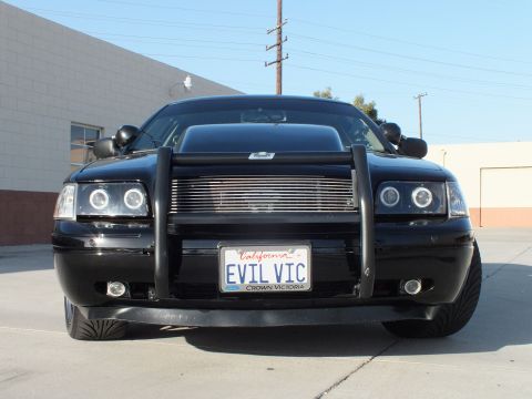 2003 Ford Crown Victoria - Head-on view of a black Ford Crown Victoria with halo headlights and a California plate reading EVIL VIC behind the push bar.