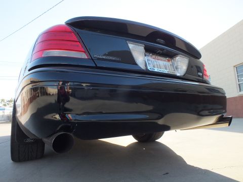 2003 Ford Crown Victoria - Low rear view of a black Ford Crown Victoria showing taillights, a Ford-framed plate, and a chrome exhaust tip.