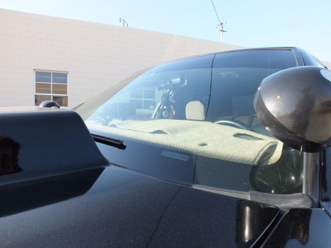 2003 Ford Crown Victoria - Close-up of a dusty windshield and cowl on a black car, with a black spotlight mounted on the A-pillar.