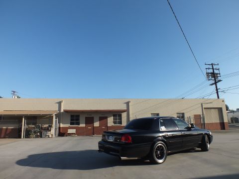 2003 Ford Crown Victoria - Rear-quarter view of a black Ford Crown Victoria on concrete with utility poles and power lines overhead.