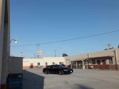 2003 Ford Crown Victoria - black sedan parked in a wide industrial yard with a streetlight and an ASCO Metals sign in the background.