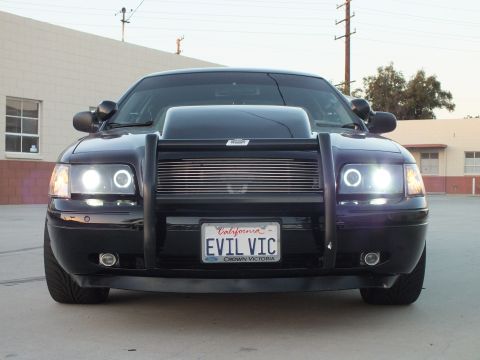 2003 Ford Crown Victoria - black Ford Crown Victoria with a push bar, billet grille and halo headlights shows a California EVIL VIC plate.