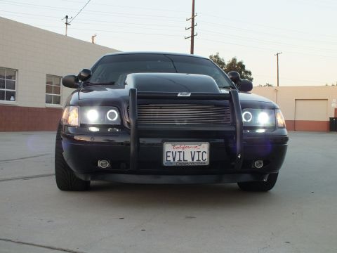2003 Ford Crown Victoria - black Ford Crown Victoria with a push bar, billet grille and bright halo headlights shows the EVIL VIC California plate.