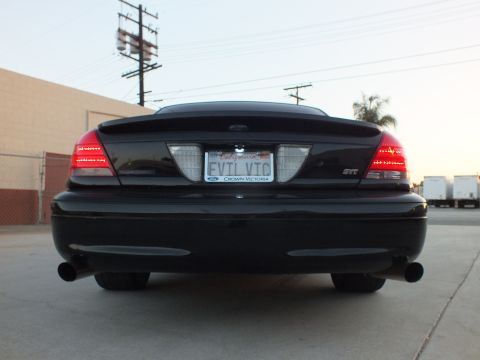 2003 Ford Crown Victoria - Rear view of a black full-size sedan with dual exhaust tips and a license plate frame reading Ford Crown Victoria.