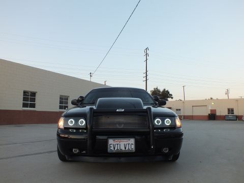 2003 Ford Crown Victoria - Head-on view of a black sedan fitted with a brush guard, halo projector headlights and an EVIL VIC plate.