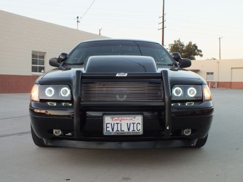 2003 Ford Crown Victoria - Head-on view of a black sedan with a brush guard, billet grille, halo headlights and an EVIL VIC plate.