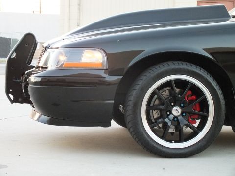 2003 Ford Crown Victoria - Close-up of a black sedan's front fender, headlight and machined-lip wheel with a red brake caliper.