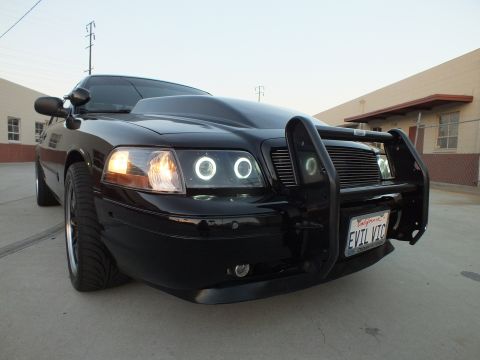 2003 Ford Crown Victoria - Low-angle front quarter of a black Ford Crown Victoria with grille guard, halo lights and California plate EVIL VIC.