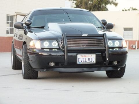 2003 Ford Crown Victoria - Front three-quarter of a black Ford Crown Victoria with grille guard, halo lights and California plate EVIL VIC.