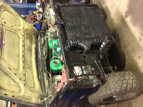 1995 Ford Bronco - The engine bay of a vehicle is shown with the hood open, revealing a large radiator and a green turbocharger.
